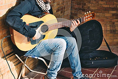 A busker playing Spanish acoustic guitar with a small amplifier in the street Stock Photo