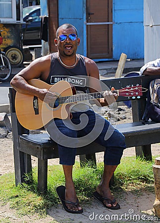 A busker plays his guitar in Grand-baie, Mauritius Editorial Stock Photo