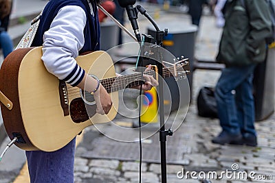 Busker. Singer guitarist with acoustic guitar. Selective focus on foreground Stock Photo