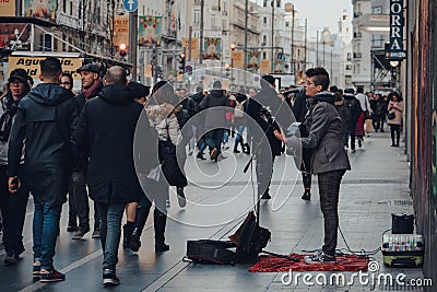 Busker singing and playing guitar on Gran Via street in Madrid, Spain, people walking past Editorial Stock Photo