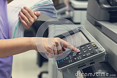 Bussinesswoman using copier machine to copy heap of paperwork in office Stock Photo