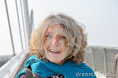 Bust portrait of smiling curly woman on bridge Stock Photo