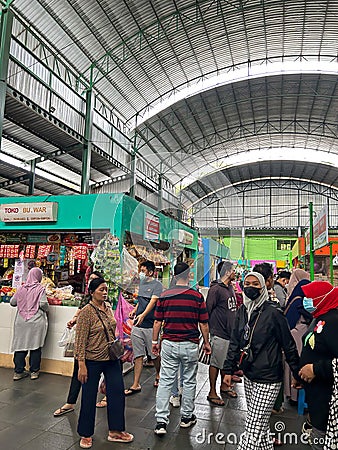 bustling atmosphere in a traditional market with a stall full of groceries and several buyers Editorial Stock Photo