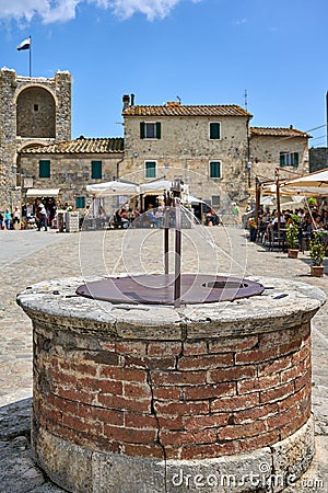 Bustling street, featuring a traditional stone well in Monteriggioni, Italy. Editorial Stock Photo