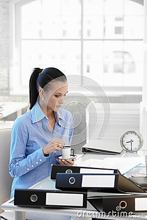 Busy businesswoman having coffee at desk Stock Photo