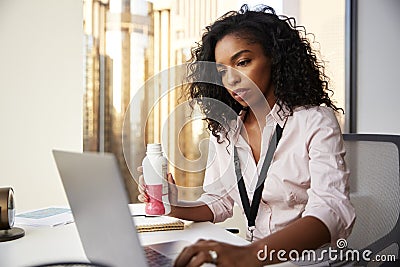 Busy Businesswoman With Laptop Sitting At Desk Having Protein Shake For Working Lunch Stock Photo