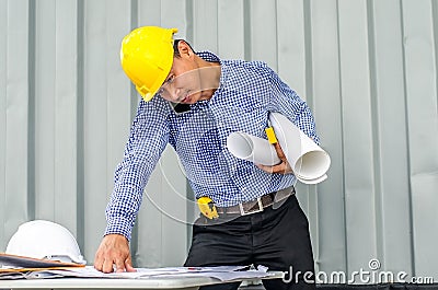 Busy construction engineer talking on phone while carrying blueprints with checking the building progress Stock Photo