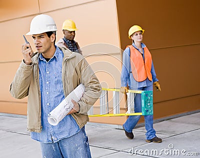 Busy construction workers carrying ladder Stock Photo