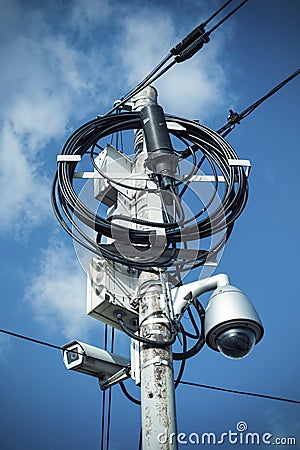 Busy electricity line and security camera against blue sky. Stock Photo