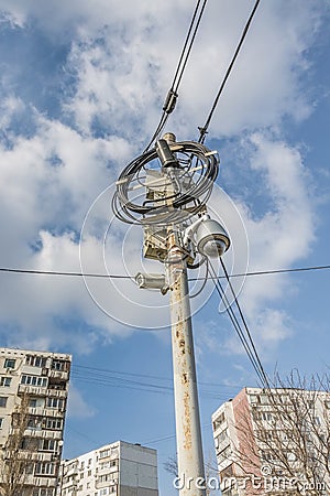 Busy electricity line and security camera against blue sky. Stock Photo