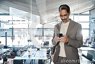 Busy mature business man wearing suit using mobile cell phone in office. Stock Photo