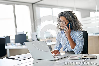 Busy mature business woman talking on phone making business call in office. Stock Photo