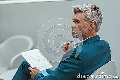 Busy Mature businessman workingon with documents while sitting in modern coworking Stock Photo
