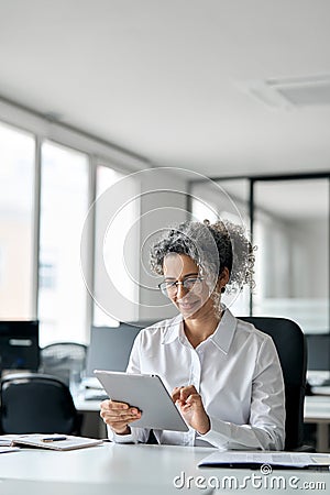 Busy mature professional business woman using tablet in office, vertical. Stock Photo