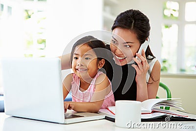 Busy Mother Working From Home With Daughter Stock Photo