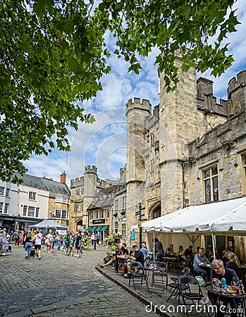 Busy outdoor cafes in front of the Penniless Porch and Bishops Palace gateway in Market Place, Wells, Somerset, UK Editorial Stock Photo