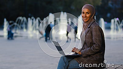 Busy successful muslim student girl in hijab young islamic business woman using laptop app working in city fountains Stock Photo