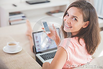 Busy woman at home using mobile phone and laptop at the same tim Stock Photo