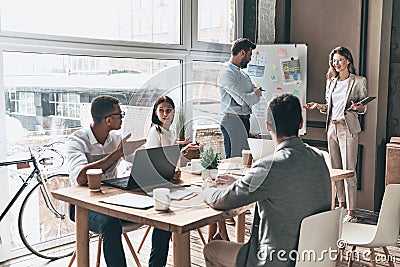 Busy working day. Two young colleagues conducting a business presentation using flipchart while working in the creative office Stock Photo