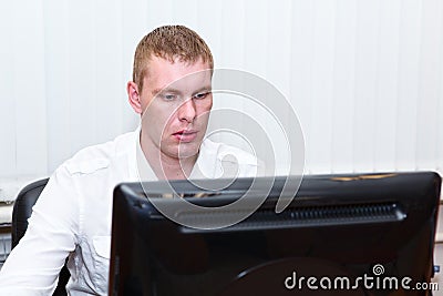 Busy young man in white shirt working at pc Stock Photo