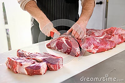 Butcher or cook slicing chuck steaks Stock Photo