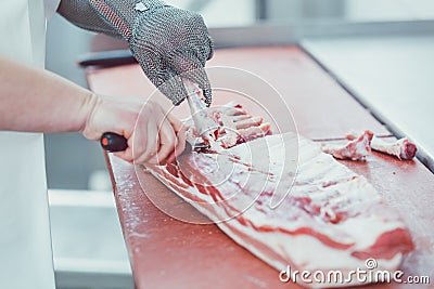 Butcher cutting meat for further processing with knife Stock Photo