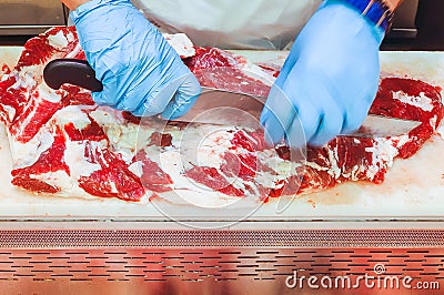 Butcher hands cutting a piece of raw veal meat or beef at the farmers market Stock Photo