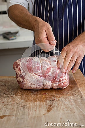 Butcher tying up a joint of ham Stock Photo