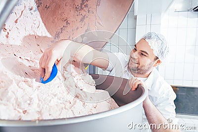 Butcher grounding meat in grinder machine to make sausages Stock Photo