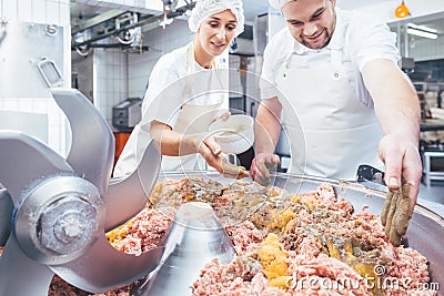 Butchers putting spices in minced meat Stock Photo