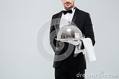 Butler in tuxedo and gloves holding silver tray with lid Stock Photo