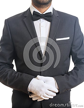 Butler, waiter with tuxedo and bow tie, folded gloved hands ready to serve, standing on white background Stock Photo