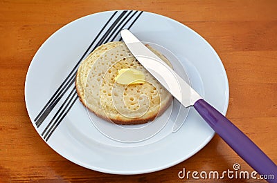 Buttered English crumpet with knife Stock Photo