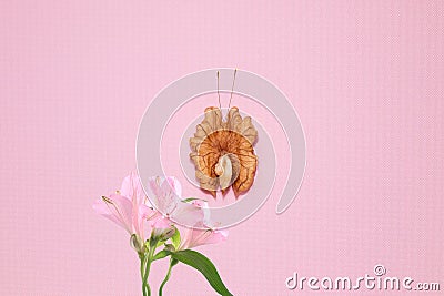A butterfly made from the grain of a peeled walnut sits on a bouquet of lilies Stock Photo