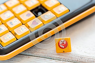 Button with an angry emoticon on the keyboard background. Close up. Concept of social networks, communication and emotions Stock Photo