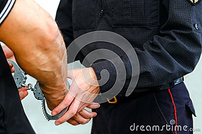 Buttons COP handcuffs an arrested criminal. The man at the police station. Handcuffs on the wrists of the detained man Stock Photo