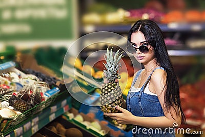 Buyer chooses pineapple in the store. Girl buys healthy fruits Stock Photo