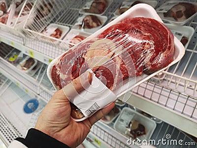 Buyer hand with beef meat packageat the grocery store. Close up of man holding wrapped meat in grocery store Stock Photo