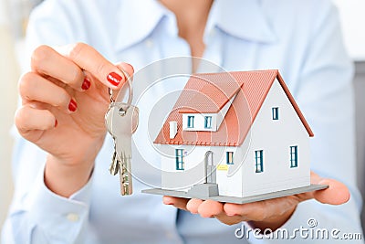 Buying a house concept with woman hands holding a model house and keys Stock Photo