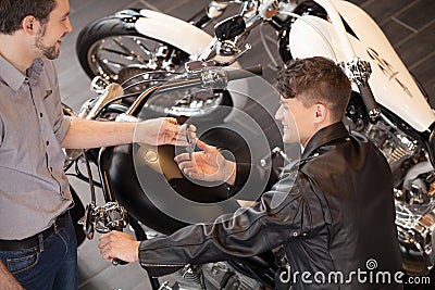 Buying a motorcycle. Top view of cheerful young sales executive Stock Photo