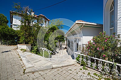 Narrow street on the island. Flowers, trees, and white houses. Buyukada Stock Photo