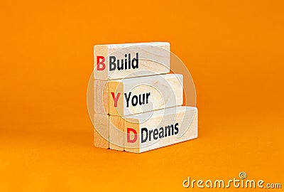 BYD build your dreams symbol. Concept words BYD build your dreams on wooden blocks on a beautiful orange table orange background. Stock Photo