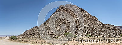 C13 gravel road and Dolerite boulders butte in Naukluft desert, north of Aus, Namibia Stock Photo