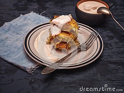 Cabbage oladi with sour cream. Against a dark background, under the plate is a blue denim napkin Stock Photo