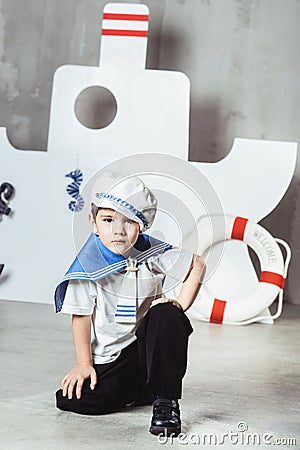 Cabin boy sitting in front of stylized ship Stock Photo