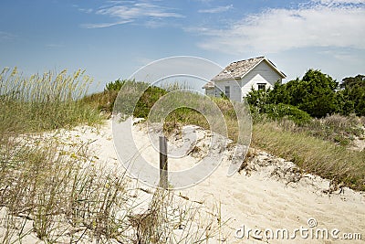 Cabin cottage small house on ocean seashore in grass and sand on a bight sunny day Stock Photo