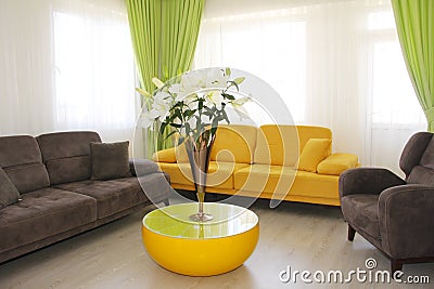 Cabin interior with yellow and brown sofas and white lilies Editorial Stock Photo