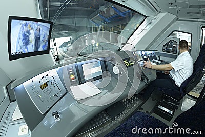 At the cabin of the passenger train. Train driver sitting of locomotive in front of the dashboard and putting hand on a start Editorial Stock Photo