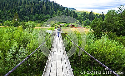 cable bridge,wooden bridge. The girl goes along the rope wooden bridge. Stock Photo