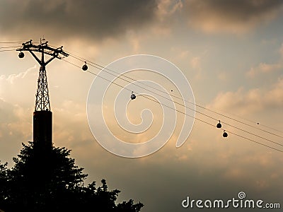 Cable cars between Singapore and Sentosa island silhouetted against dark ominous clouds Stock Photo